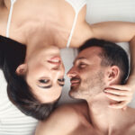 мужчина с девушкой лежат на кровати и улыбаются