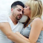 девушка лежит в обнимку с парнем и целует его